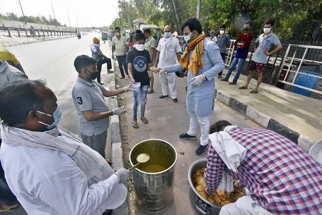 NEW DELHI, INDIA - APRIL 15: Baba Gorakhnath Dhuna Ashram workers distributing food to slum people at NH 24 near mother dairy, on day twenty two of the 21-day nationwide lockdown on April 15, 2020 in New Delhi, India. (Photo by Sanjeev Verma Hindustan Times) Government Provide Food To Homeless And Poor Amid Lockdown To Prevent Covid-19