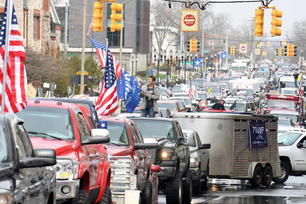April 15, 2020, Lansing, Michigan, USA: Deborah Creque waves an American flag and a Donald Trump flag as she and other protestors, from their cars and on foot, surround the State Capitol during Operation Gridlock in Lansing, Mich. on Wednesday, April 15, 2020 against some of Michigan Gov. Gretchen Whitmer s new executive orders. Lansing USA - ZUMAm67_ 20200415_zaf_m67_004 Copyright: xDanielxMearsx