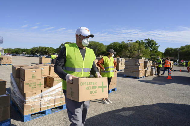 April 15, 2020, Austin, Texas, USA: Without fanfare, Texas head football coach Tom Herman volunteers putting 28-lb boxes of food into trunks of cars during a distribution drive that fed 2,500 Austin-area families on Wednesday. Texas is seeing a huge spike in food bank demand after job losses due to the coronavirus pandemic. Austin USA - ZUMAd150 20200415_znp_d150_046 Copyright: xBobxDaemmrichx