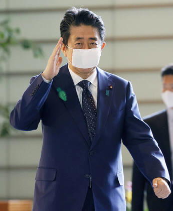 Japan PM Abe Japanese Prime Minister Shinzo Abe arrives at his office in Tokyo on April 16, 2020, wearing a face mask amid the spread of the new coronavirus. 