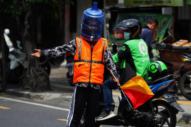 Wearing Gallons for Face Shield amid the spread of COVID-19 in Indonesia - 16 April 2020. A traffic control volunteer wearing unique face shields from used gallons in Yogyakarta, Wednesday, April 16, 2020. Ali Akbar (52) wearing unique face shield when managing traffic amid the spread of Coronavirus (COVID-19) disease. (Photo by Devi Rahman INA Photo Agency imago images) 