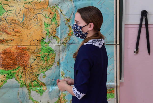 PRIMORYE TERRITORY, RUSSIA - APRIL 16, 2020: A pupil in a face mask reads a map during a geography lesson at No 8 Comprehensive School in the village of Nezhino, some 40 km north of Vladivostok. After moving to online schooling due to the COVID-19 pandemic, educational institutions in the Primorye Territory are switching back to classroom teaching, with underfilled schools being the first to welcome pupils. Yuri Smityuk TASS  TS0D5F22