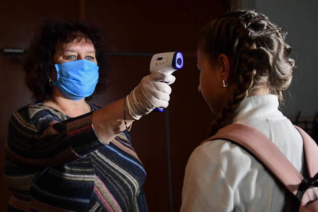 PRIMORYE TERRITORY, RUSSIA - APRIL 16, 2020: The headmistress screens a pupil s temperature at the entrance to No 8 Comprehensive School in the village of Nezhino, some 40 km north of Vladivostok. After moving to online schooling due to the COVID-19 pandemic, educational institutions in the Primorye Territory are switching back to classroom teaching, with underfilled schools being the first to welcome pupils. Yuri Smityuk TASS  TS0D5F2E