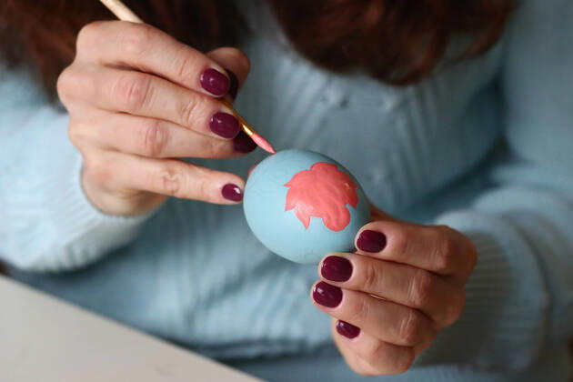 MOSCOW, RUSSIA - APRIL 16, 2020: Artist Iya Tokareva paints wooden Easter eggs Gorodets-style at her home studio; Gorodets painting, one of the traditional Russians handicrafts, originated in the middle of XIX century in the town of Gorodets, the Nizhny Novgorod Region. Anton Novoderezhkin TASS  TS0D5FF4