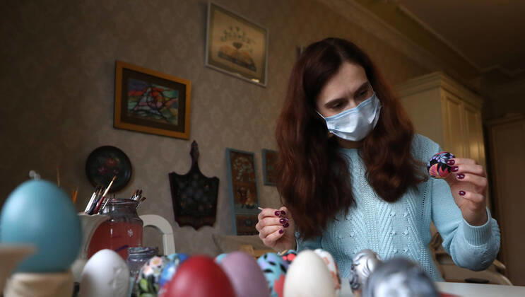 MOSCOW, RUSSIA - APRIL 16, 2020: Artist Iya Tokareva paints wooden Easter eggs Gorodets-style at her home studio; Gorodets painting, one of the traditional Russians handicrafts, originated in the middle of XIX century in the town of Gorodets, the Nizhny Novgorod Region. Anton Novoderezhkin TASS  TS0D5FDC
