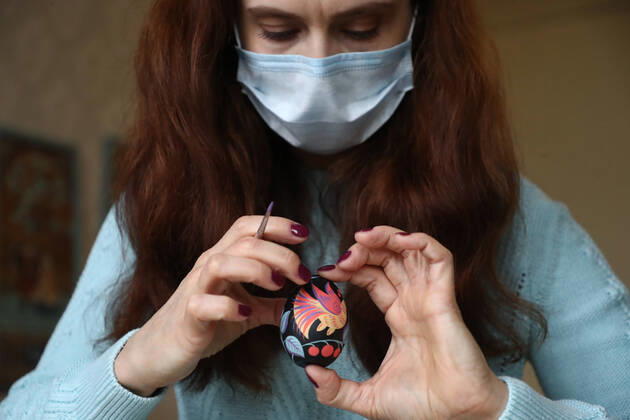 Entertainment Bilder des Tages MOSCOW, RUSSIA - APRIL 16, 2020: Artist Iya Tokareva in a face mask paints a wooden Easter egg Gorodets-style at her home studio; Gorodets painting, one of the traditional Russians handicrafts, originated in the middle of XIX century in the town of Gorodets, the Nizhny Novgorod Region. Anton Novoderezhkin TASS  TS0D5FDD