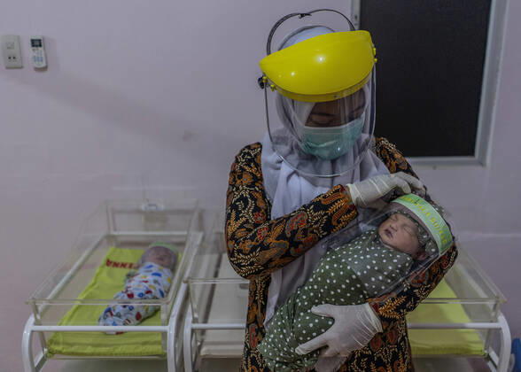 April 16, 2020, Bireuen, Aceh, Indonesia: A nurse wears a protective gear holds a newborn baby wearing a face shield as a protective measure amid fears of coronavirus disease COVID-19 at a hospital in Bireuen, Aceh province. Latest reports of COVID-19 cases, Indonesian confirms 5.516 positive cases, 548 recovered with 496 deaths. Bireuen Indonesia - ZUMAm250 20200416_zip_m250_007 Copyright: xZikrixMaulanax