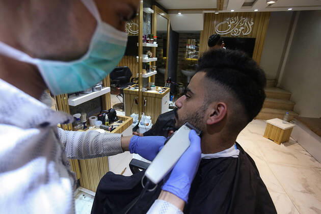 Daily Life at Barber in Southern Gaza Strip, Palestine amid Coronavirus Outbreak - 16 April 2020. A Palestinian barber wearing a face mask and a medical glove with his hand as a precautionary measure against Coronavirus (COVID-19), sterilizes his tools before cutting the customer s hair in Khan Yunis, southern Gaza Strip, Palestine, April 16, 2020. (Photo by Yousef Masoud INA Photo Agency imago images) 
