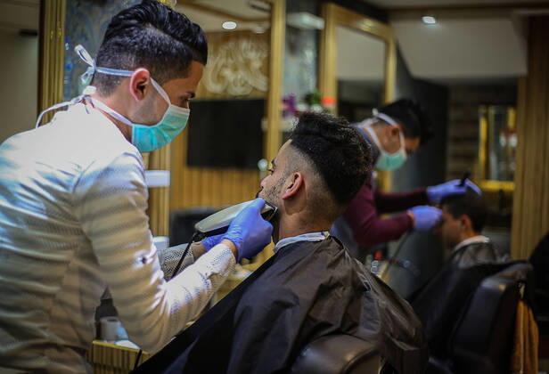 Daily Life at Barber in Southern Gaza Strip, Palestine amid Coronavirus Outbreak - 16 April 2020. A Palestinian barber wearing a face mask and a medical glove with his hand as a precautionary measure against Coronavirus (COVID-19), sterilizes his tools before cutting the customer s hair in Khan Yunis, southern Gaza Strip, Palestine, April 16, 2020. (Photo by Yousef Masoud INA Photo Agency imago images) 