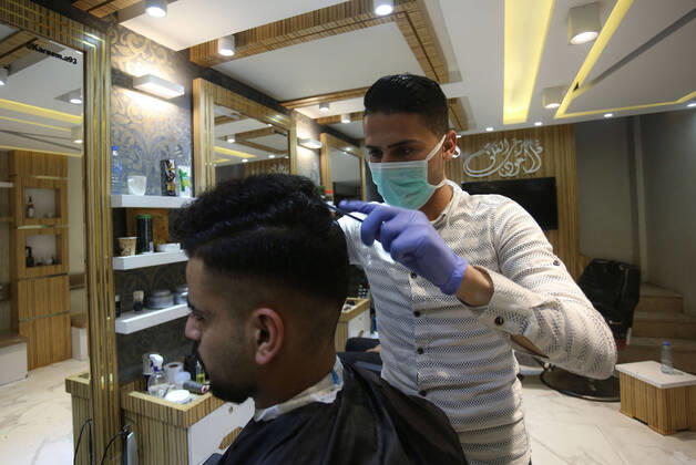 Daily Life at Barber in Southern Gaza Strip, Palestine amid Coronavirus Outbreak - 16 April 2020. A Palestinian barber wearing a face mask and a medical glove with his hand as a precautionary measure against Coronavirus (COVID-19), sterilizes his tools before cutting the customer s hair in Khan Yunis, southern Gaza Strip, Palestine, April 16, 2020. (Photo by Yousef Masoud INA Photo Agency imago images) 