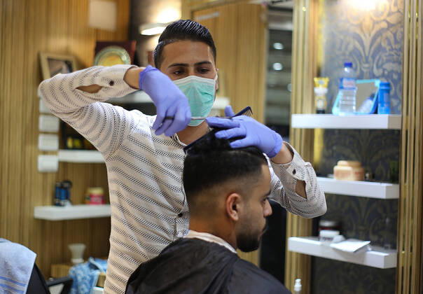 Daily Life at Barber in Southern Gaza Strip, Palestine amid Coronavirus Outbreak - 16 April 2020. A Palestinian barber wearing a face mask and a medical glove with his hand as a precautionary measure against Coronavirus (COVID-19), sterilizes his tools before cutting the customer s hair in Khan Yunis, southern Gaza Strip, Palestine, April 16, 2020. (Photo by Yousef Masoud INA Photo Agency imago images) 