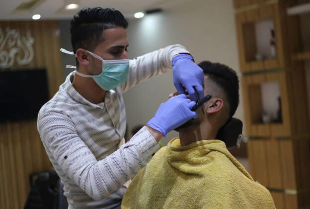 Daily Life at Barber in Southern Gaza Strip, Palestine amid Coronavirus Outbreak - 16 April 2020. A Palestinian barber wearing a face mask and a medical glove with his hand as a precautionary measure against Coronavirus (COVID-19), sterilizes his tools before cutting the customer s hair in Khan Yunis, southern Gaza Strip, Palestine, April 16, 2020. (Photo by Yousef Masoud INA Photo Agency imago images) 