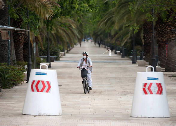 April 16, 2020, Malaga, Spain: A woman wearing a face mask rides her bike along an a empty promenade during the covid-19 crisis..Following the confinement decreed by the Spanish government and will extended until 10th May, people are confinement in their homes causing an exceptional situation of unusual urban scenes such as empty streets. Malaga Spain - ZUMAs197 20200416_zaa_s197_047 Copyright: xJesusxMeridax