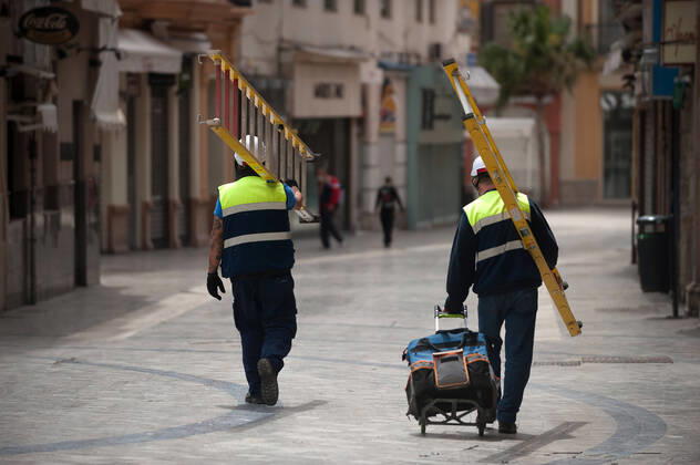 April 16, 2020, Malaga, Spain: Construction workers walking on an almost deserted street during the covid-19 crisis..Following the confinement decreed by the Spanish government and will extended until 10th May, people are confinement in their homes causing an exceptional situation of unusual urban scenes such as empty streets. Malaga Spain - ZUMAs197 20200416_zaa_s197_058 Copyright: xJesusxMeridax