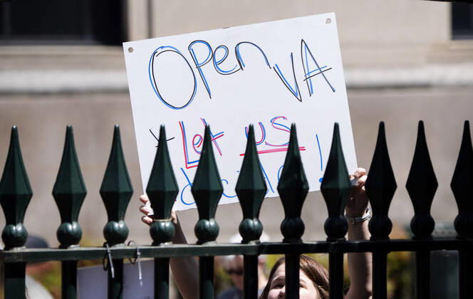 A woman with the group ReOpen Virginia participate in a protest picnic calling on an end to the Virginia Stay at Home order put in place to limit the spread of COVID-19, on the grounds of the Virginia State Capitol in Richmond on Thursday, April 16, 2020. The group is calling for Gov. Ralph Northam to end Executive Order 53 with bans gathers of over 10. Photo Kevin Dietsch  WAP20200416305 KEVINxDIETSCH