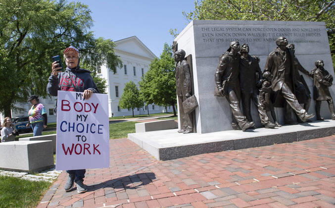 A woman with the group ReOpen Virginia participate in a protest picnic calling on an end to the Virginia Stay at Home order put in place to limit the spread of COVID-19, on the grounds of the Virginia State Capitol in Richmond on Thursday, April 16, 2020. The group is calling for Gov. Ralph Northam to end Executive Order 53 with bans gathers of over 10. Photo Kevin Dietsch  WAP20200416301 KEVINxDIETSCH