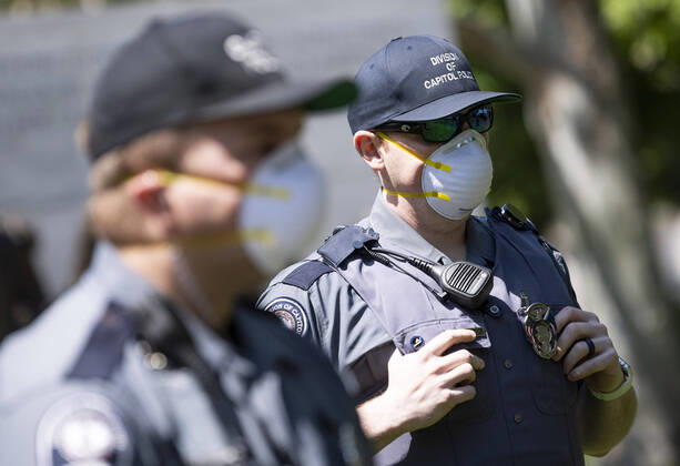 Police wear masks as they watch a protest organized by the group ReOpen Virginia calling on an end to the Virginia stay at home order put in place to limit the spread of COVID-19, on the grounds of the Virginia State Capitol in Richmond on Thursday, April 16, 2020. The group is calling for Gov. Ralph Northam to end Executive Order 53 with bans gathers of over 10. Photo Kevin Dietsch  WAP20200416311 KEVINxDIETSCH