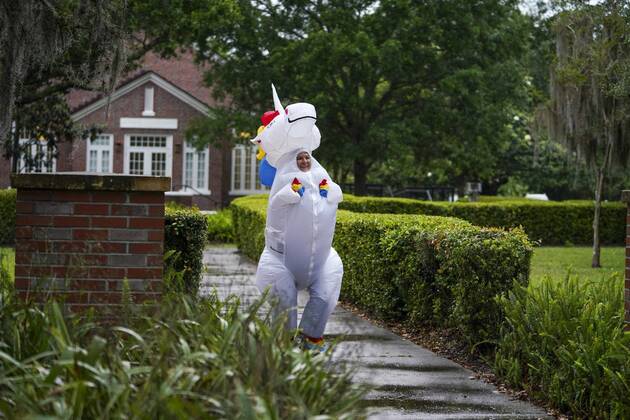April 16, 2020, Tampa, Florida, USA: After spotting a little boy, watching from his front porch and calling out to her, Corey Jurgensen stops and waves, running in place and dancing around. Jurgensen has been wearing the inflatable unicorn costume during runs, several times a week to cheer up others during this time of isolation but finds it therapeutic for herself as well, running through her Seminole Heights neighborhood wearing a silly costume. Thursday, April 16, 2020 in Tampa. Tampa USA - ZUMAs70_ 20200416_zan_s70_025 Copyright: xMarthaxAsencioxRhinex