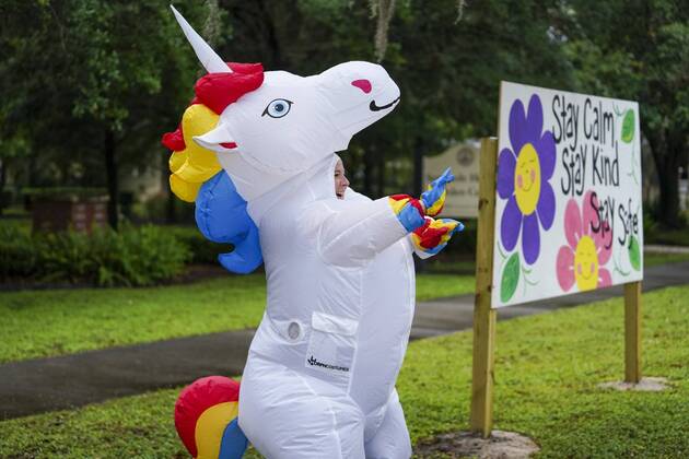April 16, 2020, Tampa, Florida, USA: Corey Jurgensen, wearing an inflatable unicorn costume, waves to passing cars. Jurgensen has been wearing the costume during runs, several times a week to cheer up others during this time of isolation but finds it therapeutic for herself as well, running through her Seminole Heights neighborhood wearing a silly costume. Thursday, April 16, 2020 in Tampa. Tampa USA - ZUMAs70_ 20200416_zan_s70_037 Copyright: xMarthaxAsencioxRhinex