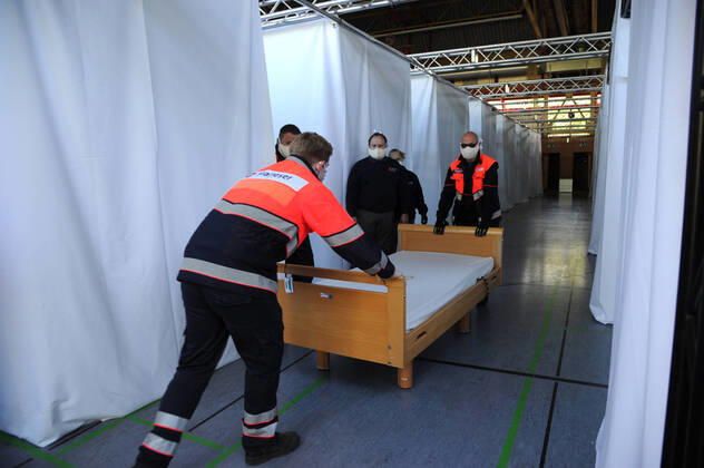 Die Sporthalle In den Fliesen in Saarlouis wird am Mittwoch (15.04.2020) wegen der Corona Krise zu einem Versogungszentrum umgebaut. Ingsgesamt 105 Betten werden in den kommenden Tagen von Hilfsorganisationen aufgestellt. Die Hilfskräfte von DRK, Malteser, THW, DRLG, BRH und der Feuerwehr Wadgassen bringen unter anderem Betten und Nachttische in die Sporthalle, wo diese dann aufgestellt und zum Teil aufgebaut werden müssen. Einige Betten kommen aus saarländischen Pflegeheimen. Heute werden 54 Pflegebetten aufgebaut. Geplant sind Dusch- und Toilettencontainer, die voraussichtlich morgen geliefert und angeschlossen werden. Wir sind lieber gut auf den Notfall vorbereitet , so Andreas Schorn, Mitarbeiter der Unterstützungsgruppe vom DRK Saarlouis.