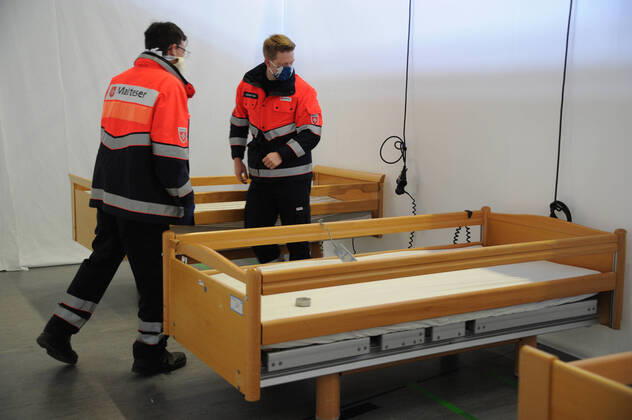 Die Sporthalle In den Fliesen in Saarlouis wird am Mittwoch (15.04.2020) wegen der Corona Krise zu einem Versogungszentrum umgebaut. Ingsgesamt 105 Betten werden in den kommenden Tagen von Hilfsorganisationen aufgestellt. Die Hilfskräfte von DRK, Malteser, THW, DRLG, BRH und der Feuerwehr Wadgassen bringen unter anderem Betten und Nachttische in die Sporthalle, wo diese dann aufgestellt und zum Teil aufgebaut werden müssen. Einige Betten kommen aus saarländischen Pflegeheimen. Heute werden 54 Pflegebetten aufgebaut. Geplant sind Dusch- und Toilettencontainer, die voraussichtlich morgen geliefert und angeschlossen werden. Wir sind lieber gut auf den Notfall vorbereitet , so Andreas Schorn, Mitarbeiter der Unterstützungsgruppe vom DRK Saarlouis.