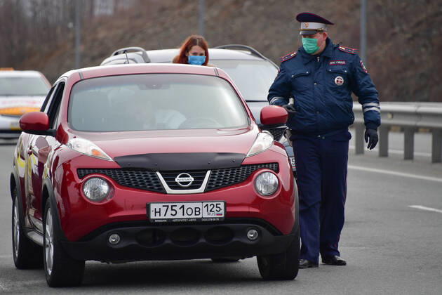 VLADIVOSTOK, RUSSIA - APRIL 17, 2020: A traffic police officer in a face mask carries out an ID check at the entrance to Russky Island in the city of Vladivostok in Russia s Far East during the pandemic of the novel coronvirus disease (COVID-19). Vladivostok s traffic police have set up a checkpoint at the approach to the bridge to stop vehicles and see if drivers and cyclists have permission to travel to Russky Island during the lockdown. Vladivostok s authorities have restricted access to Russky Island and a few smaller islands -- popular weekend retreats -- to prevent people from violating lockdown measures. Only those who live, work or study on the islands are allowed to travel. Since 31 March 2020, the Primorye Territory, including Vladivostok, has been on lockdown to counter the spread of the infection. As of 17 April 2020, the Pri  TS0D6114