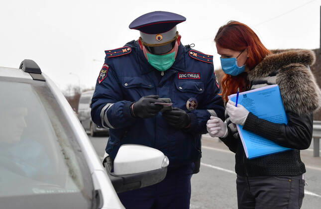VLADIVOSTOK, RUSSIA - APRIL 17, 2020: A traffic police officer in a face mask carries out an ID check at the entrance to Russky Island in the city of Vladivostok in Russia s Far East during the pandemic of the novel coronvirus disease (COVID-19). Vladivostok s traffic police have set up a checkpoint at the approach to the bridge to stop vehicles and see if drivers and cyclists have permission to travel to Russky Island during the lockdown. Vladivostok s authorities have restricted access to Russky Island and a few smaller islands -- popular weekend retreats -- to prevent people from violating lockdown measures. Only those who live, work or study on the islands are allowed to travel. Since 31 March 2020, the Primorye Territory, including Vladivostok, has been on lockdown to counter the spread of the infection. As of 17 April 2020, the Pri  TS0D611C