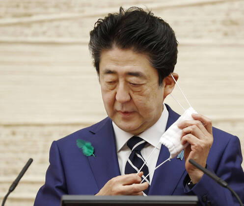 Japan PM Abe on coronavirus situation Japanese Prime Minister Shinzo Abe takes his mask off before speaking at a press conference in Tokyo on April 17, 2020. Tokyo reported a record-high 201 new coronavirus cases the same day. 