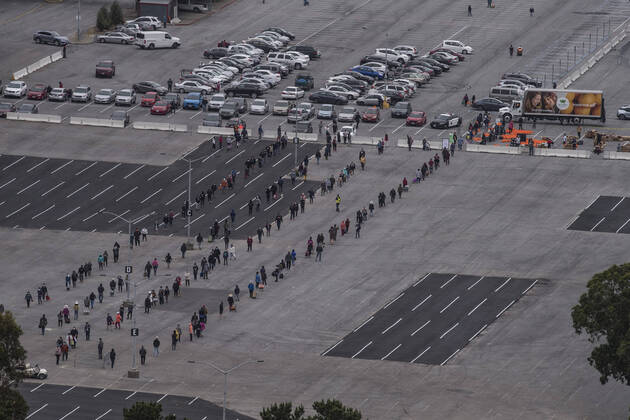 People line up to receive bags of food from the San Francisco-Marin Food Bank in the parking lot of the Cow Palace in Daly City, California on Friday, April 17, 2020. Local food banks have moved into high gear as the Coronavirus has hit the food insecure especially hard.  SXP2020041616 TERRYxSCHMITT