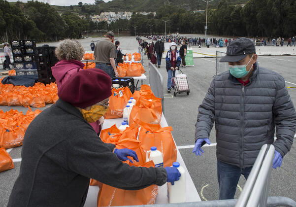 People receive bags of food from the San Francisco-Marin Food Bank in the parking lot of the Cow Palace in Daly City, California on Friday, April 17, 2020. Local food banks have moved into high gear as the Coronavirus has hit the food insecure especially hard.  SXP2020041619 TERRYxSCHMITT