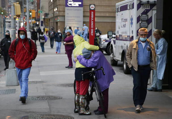 A healthcare worker embraces a lady on a bicycle outside of NYU Langone hospital when FDNY firefighters, NYPD police officers and pedestrians applaud and show their gratitude to medical staff and essential workers on the front lines of the coronavirus pandemic in New York City on on Friday, April 17, 2020. The city s coronavirus death toll continued to climb with over 700 new COVID-19 fatalities bringing the total to over 12,000 to date.  NYP20200417111 JOHNxANGELILLO
