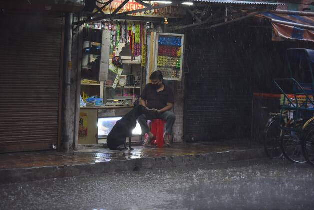 NEW DELHI, INDIA - APRIL 18: A man and a dog outside a shop while it rains heavily near Pandav Nagar during lockdown, on April 18, 2020 in New Delhi, India. (Photo by Raj K Raj Hindustan Times ) Heavy Rainfall In Delhi-NCR