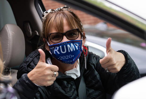 A woman wears a Trump face mask as she participates in a car protest to reopen Maryland and end the stay at home order imposed during the Coronavirus COVID-19 pandemic, near the state capitol building in Annapolis, Maryland on Saturday, April 18, 2020.  WAP20200418307 KEVINxDIETSCH
