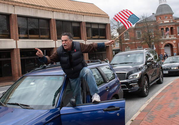 A man yells from the door of his vehicle during a car protest to reopen Maryland and end the stay at home order imposed during the Coronavirus COVID-19 pandemic, near the state capitol building in Annapolis, Maryland on Saturday, April 18, 2020. Drivers circled Annapolis hoking their horns and calling for Gov. Larry Hogan (R-MD) to end the stay at home order.  WAP20200418338 KEVINxDIETSCH