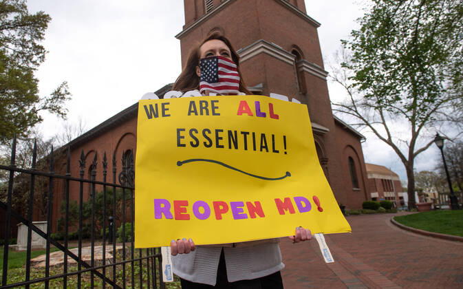 A protester holds a sign during a car protest to reopen Maryland and end the stay at home order imposed during the Coronavirus COVID-19 pandemic, near the state capitol building in Annapolis, Maryland on Saturday, April 18, 2020. Drivers circled Annapolis hoking their horns and calling for Gov. Larry Hogan (R-MD) to end the stay at home order.  WAP20200418348 KEVINxDIETSCH