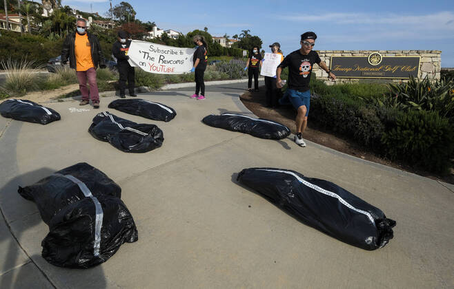 April 18, 2020, Los Angeles, California, U.S: A man runs between demonstrators and fake body bags outside Trump National Golf Club Los Angeles in protest against U.S. President Donald Trump s response to the coronavirus disease (COVID-19) pandemic, in Rancho Palos Verdes, California, April 18, 2020. Los Angeles U.S. - ZUMAc68_ 20200418_zaf_c68_015 Copyright: xRingoxChiux