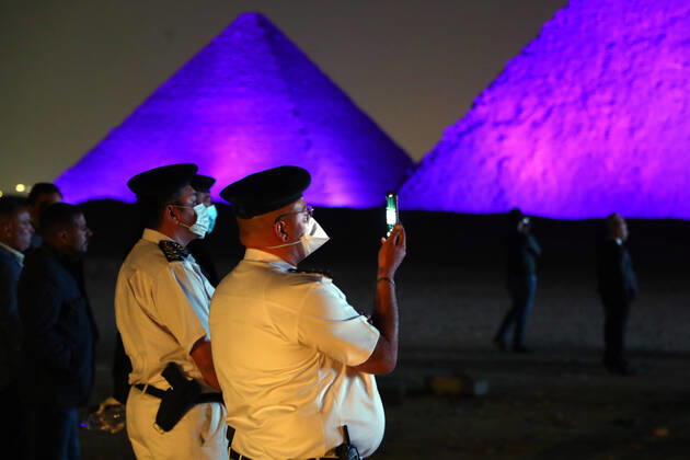 (200418) -- GIZA (EGYPT), April 18, 2020 (Xinhua) -- A man takes photos near the illuminated Giza pyramids during the World Heritage Day amid the COVID-19 pandemic in Giza, Egypt, on April 18, 2020. Egypt reported on Saturday 188 new COVID-19 cases, the highest daily increase, bringing the number of confirmed positive cases in the country to 3,032. (Xinhua Ahmed Gomaa) EGYPT-GIZA-PYRAMIDS-COVID-19-WORLD HERITAGE DAY-ILLUMINATION 