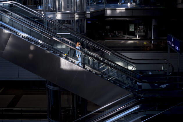 Hauptbahnhof Berlin - Corona-Zeiten DEU, Deutschland, Germany, Berlin, 19.04.2020 Passagier mit Maske auf der sonst leeren Rolltreppe im Hauptbahnhof Berlin der DB Deutsche Bahn zu Zeiten der Corona-Krise und einer Ausgangssperre. Lonely passanger with protection mask on an escalator at the otherwise empty railway station of the German railway company DB Deutsche Bahn at the main station Hauptbahnhof in times during the Corona crises and a lookout in Berlin, Germany.