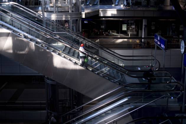 Hauptbahnhof Berlin - Corona-Zeiten DEU, Deutschland, Germany, Berlin, 19.04.2020 Passagier mit Maske auf der sonst leeren Rolltreppe im Hauptbahnhof Berlin der DB Deutsche Bahn zu Zeiten der Corona-Krise und einer Ausgangssperre. Lonely passanger with protection mask on an escalator at the otherwise empty railway station of the German railway company DB Deutsche Bahn at the main station Hauptbahnhof in times during the Corona crises and a lookout in Berlin, Germany.