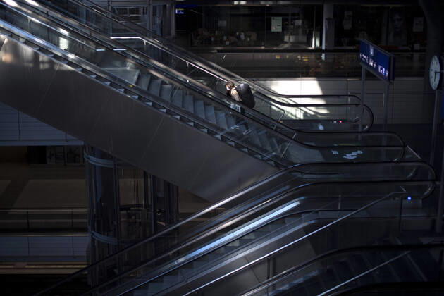 Hauptbahnhof Berlin - Corona-Zeiten DEU, Deutschland, Germany, Berlin, 19.04.2020 Passagier mit Maske auf der sonst leeren Rolltreppe im Hauptbahnhof Berlin der DB Deutsche Bahn zu Zeiten der Corona-Krise und einer Ausgangssperre. Lonely passanger with protection mask on an escalator at the otherwise empty railway station of the German railway company DB Deutsche Bahn at the main station Hauptbahnhof in times during the Corona crises and a lookout in Berlin, Germany.