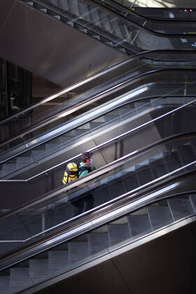 Hauptbahnhof Berlin - Corona-Zeiten DEU, Deutschland, Germany, Berlin, 19.04.2020 Passagier mit Maske auf der sonst leeren Rolltreppe im Hauptbahnhof Berlin der DB Deutsche Bahn zu Zeiten der Corona-Krise und einer Ausgangssperre. Lonely passanger with protection mask on an escalator at the otherwise empty railway station of the German railway company DB Deutsche Bahn at the main station Hauptbahnhof in times during the Corona crises and a lookout in Berlin, Germany.
