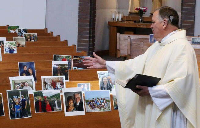 Rev. Bob Evans talks to photos of his parishioners during his Sunday service at the Holy Spirit Catholic Church in Maryland Heights, Missouri on Sunday, April 19, 2020. Since members cannot attend in person because of the Coronavirus pandemic, Evans asked for his church to send in photos of themselves receiving over 500 photos from his 1500 membership. The photos are taped to the pews where the family sits, while he preforms the weekly service via Facebook live.  SLP2020041909 BILLxGREENBLATT