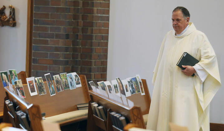 Rev. Bob Evans talks to photos of his parishioners during his Sunday service at the Holy Spirit Catholic Church in Maryland Heights, Missouri on Sunday, April 19, 2020. Since members cannot attend in person because of the Coronavirus pandemic, Evans asked for his church to send in photos of themselves receiving over 500 photos from his 1500 membership. The photos are taped to the pews where the family sits, while he preforms the weekly service via Facebook live.  SLP2020041910 BILLxGREENBLATT
