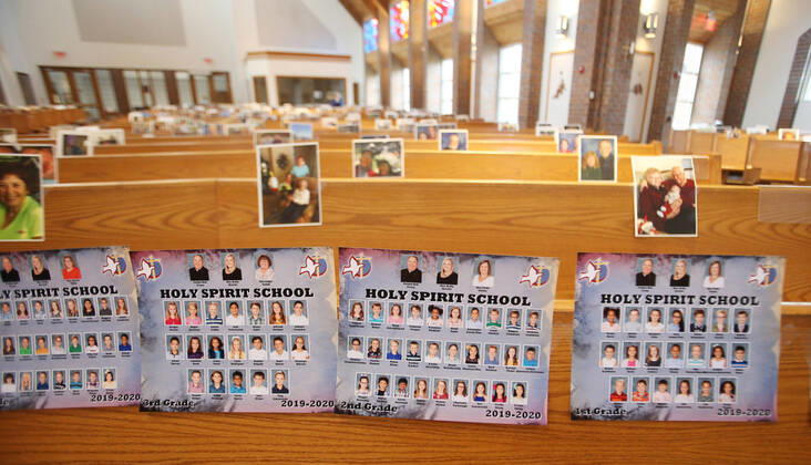 Photos of church class parishioners, sit in the first row, waiting for the start of Rev. Bob Evans Sunday service at the Holy Spirit Catholic Church in Maryland Heights, Missouri on Sunday, April 19, 2020. Since members cannot attend in person because of the Coronavirus pandemic, Evans asked for his church to send in photos of themselves receiving over 500 photos from his 1500 membership. The photos are taped to the pews where the family sits, while he preforms the weekly service via Facebook live.  SLP2020041915 BILLxGREENBLATT