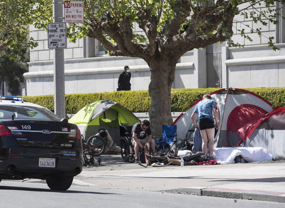 Police pass a homeless encampment in the civic center in San Francisco on Sunday, April 19, 2020. San Francisco Mayor London Breed says that efective now, face masks must be worn outside the home to protect against coronavirus.  SXP2020041904 TERRYxSCHMITT