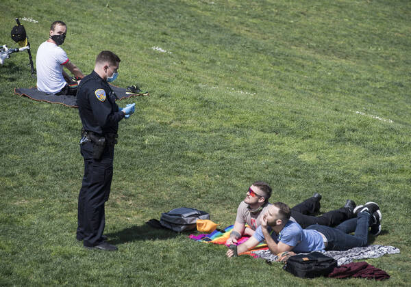 A police officer speaks with a couple on the grass at Delores Park in San Francisco on Sunday, April 19, 2020. San Francisco Mayor London Breed says that efective now, face masks must be worn outside the home to protect against coronavirus.  SXP2020041902 TERRYxSCHMITT
