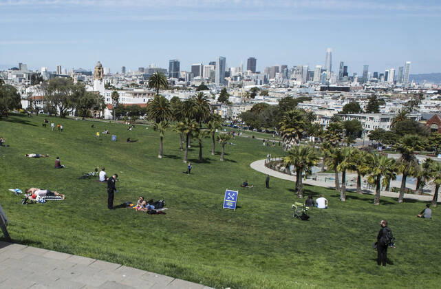 A police officer speaks with a couple on the grass at Delores Park in San Francisco on Sunday, April 19, 2020. San Francisco Mayor London Breed says that efective now, face masks must be worn outside the home to protect against coronavirus.  SXP2020041911 TERRYxSCHMITT