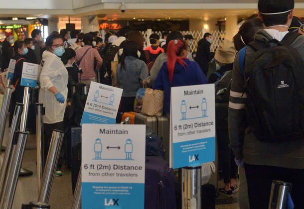 Hundreds of passengers form a line to check-in and board a China Southern Airlines midnight flight to China on Sunday, April 19, 2020 in Los Angeles. Passengers at the front of the line arrived at 5:30 a.m., with many others standing in line since 8 a.m. to ensure they would have a seat before the plane was full. Mayor Eric Garcetti said 95% of air travel has stopped in his city as Los Angeles sees the biggest drop of airplane travel in LAX history.  LAP2020041912 JIMxRUYMEN