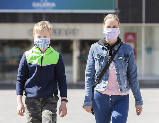 Deutschland, , , 20.04.2020, Presse, COVID-19 Deutschland faehrt langsam wieder hoch Bild: In Hessen haben die Geschaefte wieder geoeffnet, in Bayern nicht. Das wirkt sich vor allem auf die Osthessische Stadt Fulda aus, die nicht weit von der Bayerischen Landesgrenze entfernt liegt. Eine Frau und ein Kind laufen mit Mundschutz durch Fulda. Im Hintergrund ist die Karstadt Filliale, die allerdings noch geschlossen bleiben muss. Copyright: HMBxMedia OliverxMueller