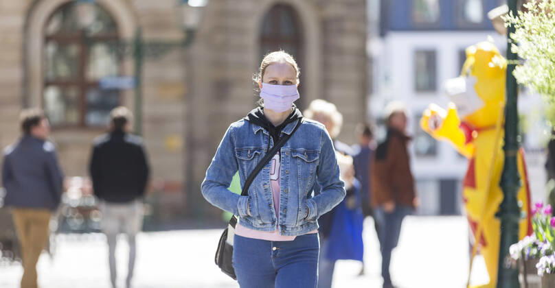 Deutschland, , , 20.04.2020, Presse, COVID-19 Deutschland faehrt langsam wieder hoch Bild: In Hessen haben die Geschaefte wieder geoeffnet, in Bayern nicht. Das wirkt sich vor allem auf die Osthessische Stadt Fulda aus, die nicht weit von der Bayerischen Landesgrenze entfernt liegt. Eine Frau läuft mit Mundschutz durch Fulda. Copyright: HMBxMedia OliverxMueller